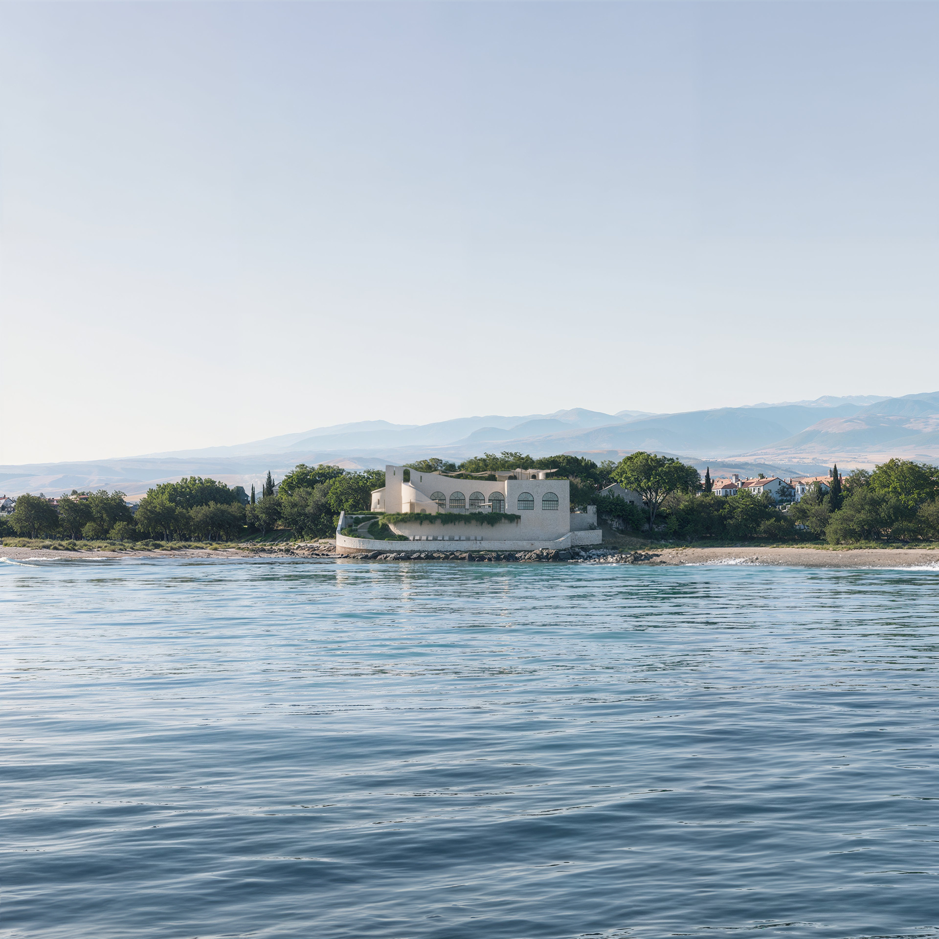 Photorealistic rendering of a coastal villa surrounded by trees, viewed from across calm water.